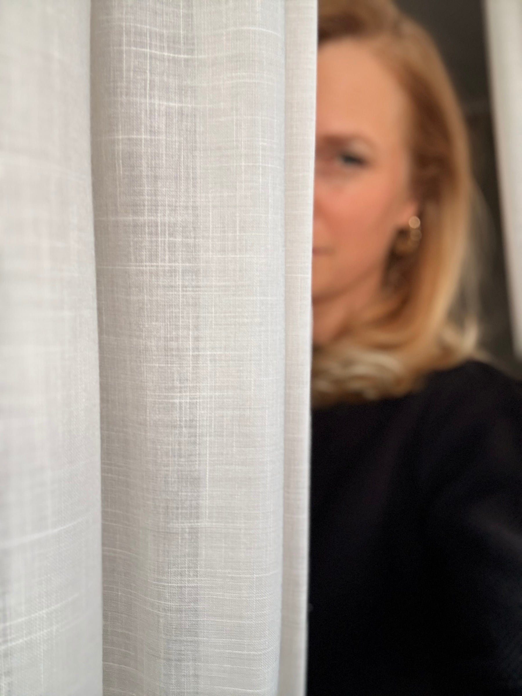 Rustig portret van Erika Vos achter een linnen gordijn